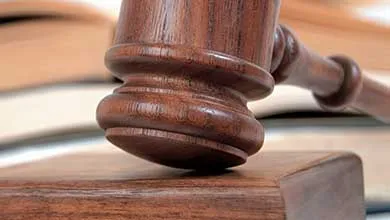 Wooden gavel on sounding block, open book in background.