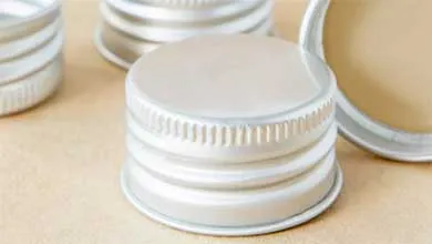 Close-up of several silver, ridged metal screw caps on a light brown surface.