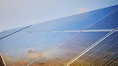 Close-up of a row of angled solar panels reflecting the golden glow of a rising or setting sun.