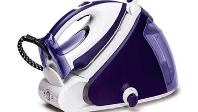 White and purple steam generator iron on its base station, isolated on a white background.