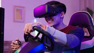 Man wearing a VR headset smiles while using a racing wheel controller.