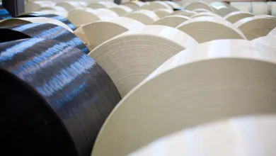 Rows of large rolled materials arranged across an industrial factory floor.