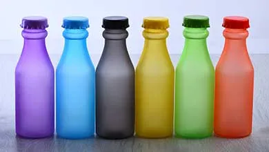 Six frosted bottles with matching colored caps—purple, light blue, dark gray, yellow, green, and orange—lined up against a plain white background.