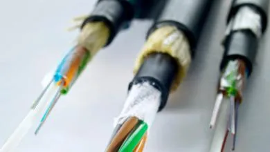 Close-up of three thick electrical cables with black sheathing partially removed, exposing colorful insulated wires inside.