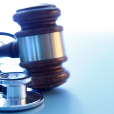 A gavel and a stethoscope on a blue background representing the intersection of the medical and legal industries.